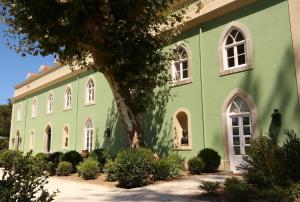 een groen gebouw met witte ramen en een boom bij Casa Holstein Quinta de Sao Sebastiao Sintra in Sintra