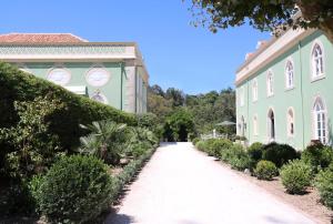 a walkway leading to a building with bushes and trees at Casa Holstein Quinta de Sao Sebastiao Sintra in Sintra
