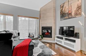 a living room with a couch and a flat screen tv at Condo Ski-In Ski-Out Stoneham in Stoneham