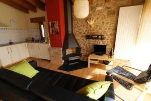 sala de estar con sofá negro y chimenea en El Mas Prat, en Vall de Bianya