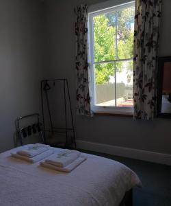 a bedroom with a bed and a window with towels on it at Milton Cottage in Napier