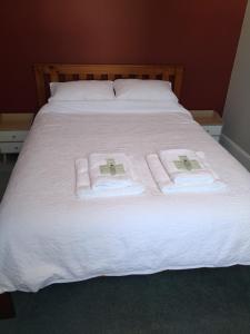 a bed with white sheets and towels on it at Milton Cottage in Napier
