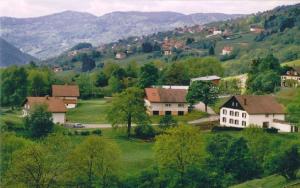 un groupe de maisons sur une colline avec des montagnes en arrière-plan dans l'établissement Les Chantenées, à La Bresse