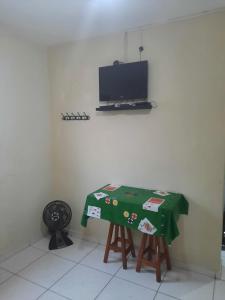 a room with a table with a television on a wall at Kit Ocian in Praia Grande