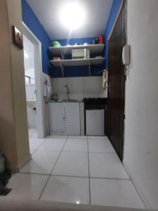 a small kitchen with blue walls and a white tile floor at Kit Ocian in Praia Grande