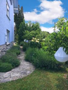 a yard with a blue house and a garden with a vase at The Lovely Garden House in Zagreb