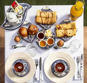 einen Tisch mit Teller und Tassen Kaffee und Essen in der Unterkunft Riad Luciano Hotel and Spa in Marrakesch
