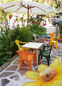un patio con mesas, sillas y una sombrilla en Karampela Rooms, en Loutra Edipsou