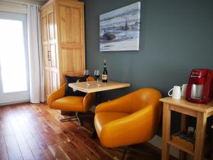 une salle à manger avec des chaises orange et une table dans l'établissement Au Cachalot Caché le gîte hôtel, à Tadoussac