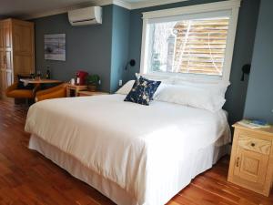 um quarto com uma cama branca e uma janela em Au Cachalot Caché le gîte hôtel em Tadoussac