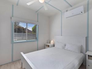 a white bedroom with a white bed and a window at Pacific Family Retreat in Long Jetty