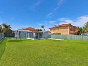un patio con un aro de baloncesto y una casa en Pacific Family Retreat, en Long Jetty