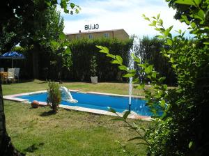 a swimming pool with a fountain in a yard at Hostal Restaurante Carolina in Pedrosillo el Ralo