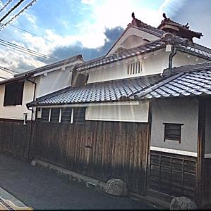 una casa con una valla de madera delante de ella en 古民家民泊かえるて, en Kashihara