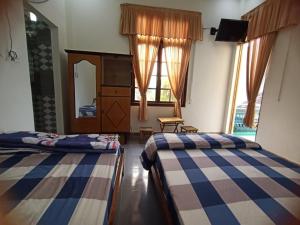 a bedroom with two beds and a dresser and a mirror at Noel Homestay in Hiếu Xương
