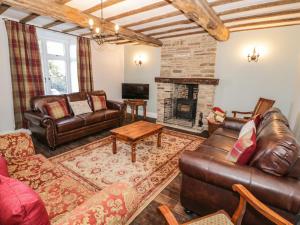 sala de estar con muebles de cuero y chimenea en Lea Farm House en Kidderminster