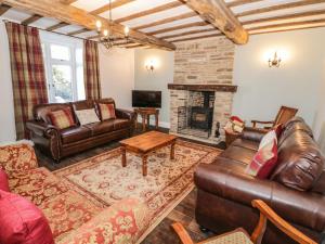 a living room with leather furniture and a fireplace at Lea Farm House in Kidderminster