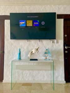 einen Glastisch mit einem TV an der Wand in der Unterkunft Terrazas del Mar II - Ocean View Apartment in Guayacanes