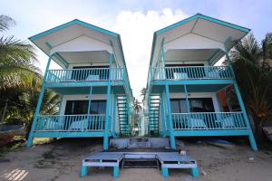 two houses on the beach with benches in front at Pondok Beach Shack in Tioman Island