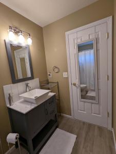 a bathroom with a sink and a mirror and a door at Contemporary 2-Bedroom Close to Downtown, Dining in Eugene