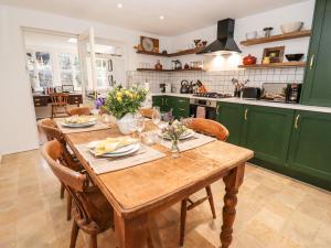 a kitchen with a wooden table and green cabinets at Royal Oak Cottage in Chipping Campden