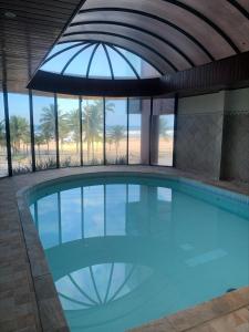 a large swimming pool with an umbrella in a building at Apto frente à praia - Guilhermina in Praia Grande