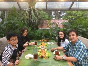 a group of people sitting around a table with food at Apartemen Ciumbuleuit 2 in Bandung