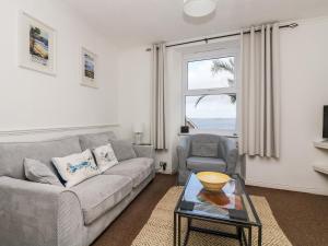 een woonkamer met een bank, een stoel en een tafel bij Lookout Cottage in Penzance