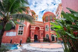 a red building with a palm tree in front of it at Sonia residence - SHA Extra Plus in Jomtien Beach