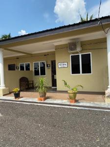 une maison jaune avec des plantes en pot devant dans l'établissement D`Cycas Homestay Pulau Indah, à Pulau Indah