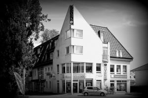 Un bâtiment blanc avec une voiture garée devant. dans l'établissement Hotel Jahnke, à Neubrandenbourg