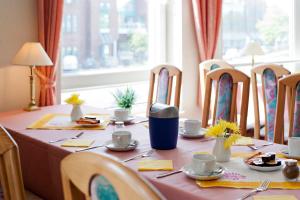una mesa de comedor con un mantel rosa y sillas en Hotel Jahnke, en Neubrandenburg