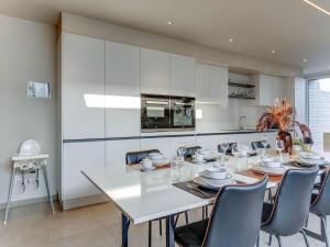 cocina blanca con mesa de comedor y sillas en Lovely Holiday Home in Roesbrugge with Sauna and bubble bath, en Roesbrugge-Haringe