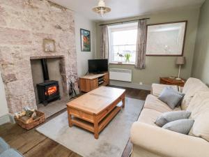 un soggiorno con divano e camino di Gamekeepers Cottage a Chillingham