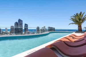 una piscina con una palmera y la ciudad en The Gallery Residences Broadbeach en Gold Coast