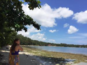 a woman standing on a beach near the water at Salty Dog Hostel in Telukdalam