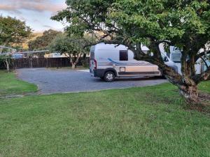 a white caravan parked next to a tree at Harbourside 29B ~ Boat Parking in Coromandel Town