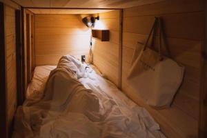 a bed in a wooden room with a white blanket at FOLK FOLK Hostel, Cafe & Bar in Ise