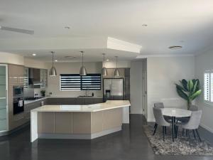 cocina con isla, mesa y sillas en Luxury home with huge pool and putting green! en Townsville