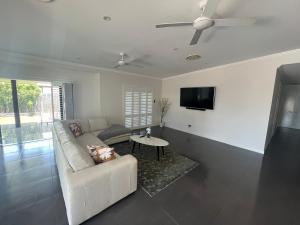 a living room with a white couch and a tv at Luxury home with huge pool and putting green! in Townsville