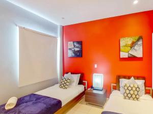 two beds in a room with an orange wall at The Best Ocean and Mountain views in the city in Jacó