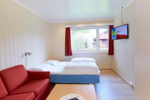 a small bedroom with a bed and a red couch at Skjåk Turistheim in Skjåk