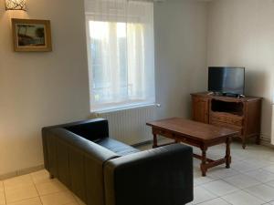 ein Wohnzimmer mit einem Sofa, einem Tisch und einem TV in der Unterkunft Gîte Velle-sur-Moselle, 3 pièces, 5 personnes - FR-1-584-178 in Velle-sur-Moselle
