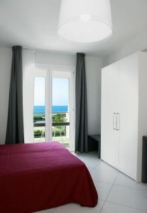 a bedroom with a red bed and a view of the ocean at Brezza Di Grecale in Trapani