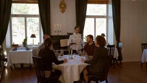 grupa ludzi siedzących przy stole w restauracji w obiekcie Sjövillan Bed & Breakfast w mieście Sandöverken