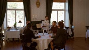 a group of people sitting around a table in a restaurant at Sjövillan Bed & Breakfast in Sandöverken