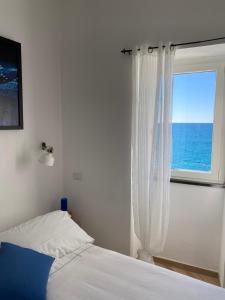 a bedroom with a bed and a window with the ocean at La Bloo di Vernazza - Sea View - AC&WiFi - Vernazzarentals in Vernazza