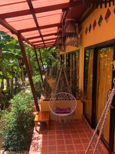 een veranda met een schommel op een huis bij One World Bungalows in Koh Lanta