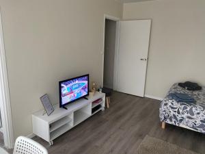 ein Wohnzimmer mit einem TV auf einem weißen Schrank in der Unterkunft Appartement Parc de Fresnoy in Roye