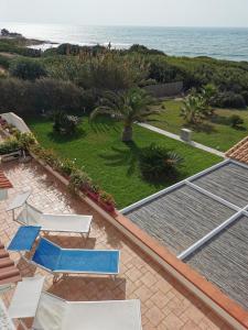 una vista aerea su un cortile con sedie e sull'oceano di TRAVELLIVING - Casa Vacanze Villa Ida, Beachfront a Punta Braccetto